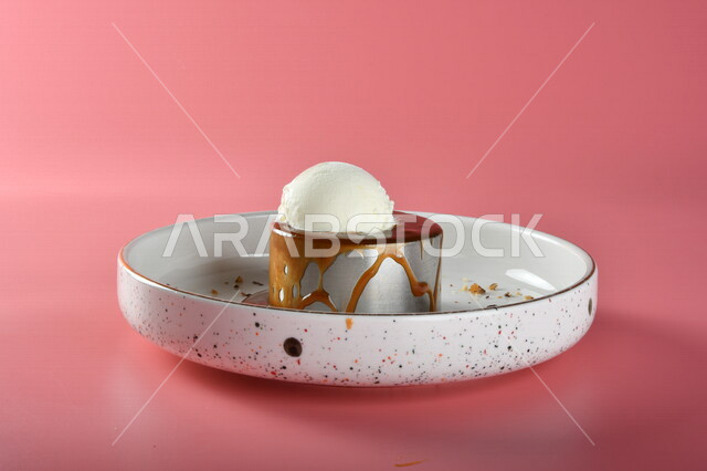 طبق من حلا كيك الشوكولاته المزينة بقطعة آيس كريم بنكهة الفانيليا ، حلا شرقي ، حلويات رمضانية ، حلويات وسكريات ، قطع الحلوى الشهية ، التحلاية ، حلويات باردة لذيذة ، خلفية ملونة