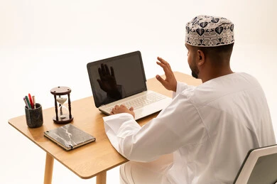 رجل عماني يستخدم الكمبيوتر المحمول لمكالمة فيديو بمكتب