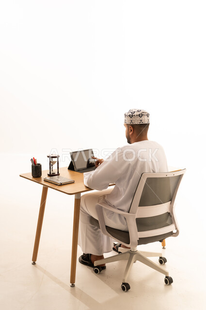 رجل عماني يستخدم جهاز لوحي على مكتب العمل