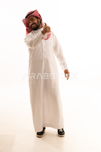 رجل سعودي بالزي التقليدي يشير بعلامة الإعجاب