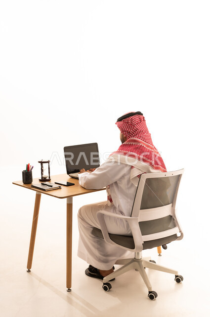 رجل سعودي يعمل على الحاسوب المحمول في المكتب