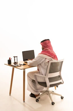 رجل سعودي يعمل على الحاسوب المحمول في المكتب