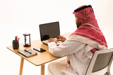 Saudi Man in Traditional Attire Working on Laptop