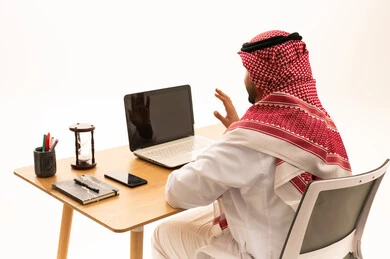 رجل سعودي يستخدم الكمبيوتر المحمول على مكتب عمل