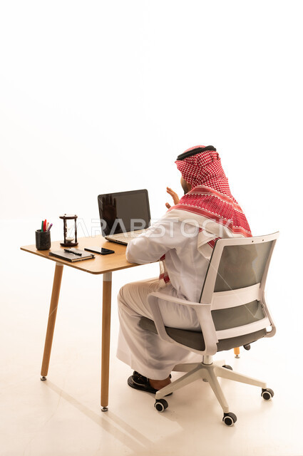 رجل سعودي يستخدم الحاسوب المحمول في مكتب عمل هادئ