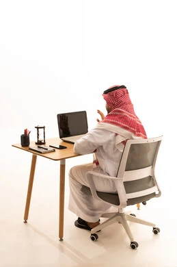Saudi Man Using Laptop at Desk in Minimalist Office