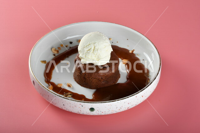 طبق من حلا كيك الشوكولاته المزينة بقطعة آيس كريم بنكهة الفانيليا ، حلا شرقي ، حلويات رمضانية ، حلويات وسكريات ، قطع الحلوى الشهية ، التحلاية ، حلويات باردة لذيذة ، خلفية ملونة