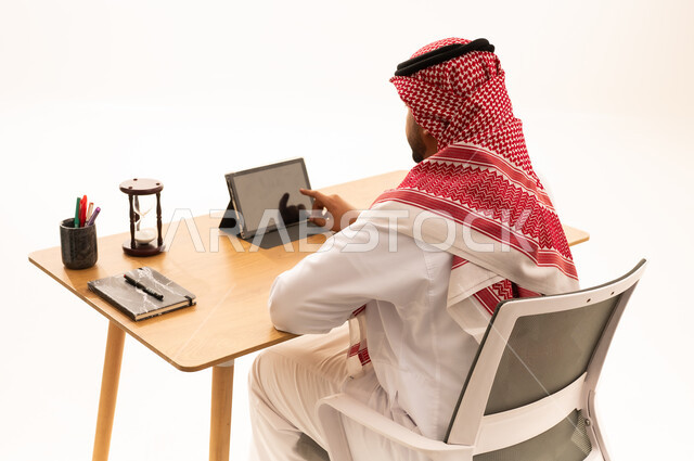 رجل أعمال سعودي باللباس التقليدي يستخدم تابلت