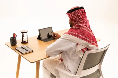 رجل أعمال سعودي باللباس التقليدي يستخدم تابلت