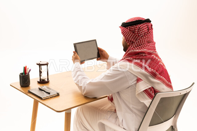 رجل سعودي يستخدم جهاز لوحي على مكتب العمل