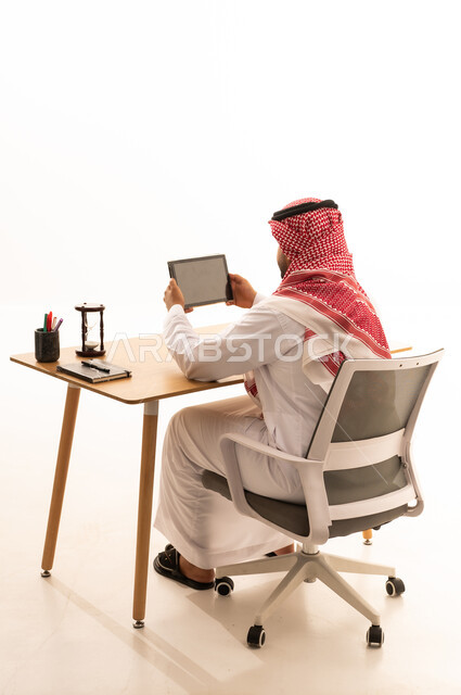 رجل سعودي يستخدم الجهاز اللوحي على مكتب العمل