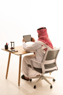 رجل سعودي يستخدم الجهاز اللوحي على مكتب العمل