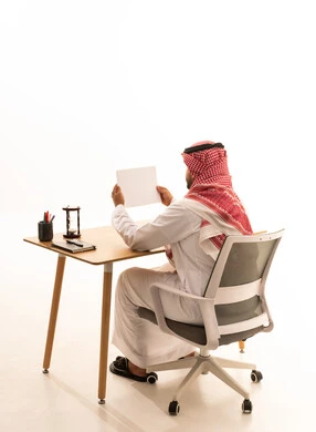 رجل سعودي باللباس التقليدي خلف مكتب عمل