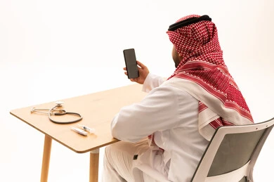Saudi Man at Medical Desk with Smartphone