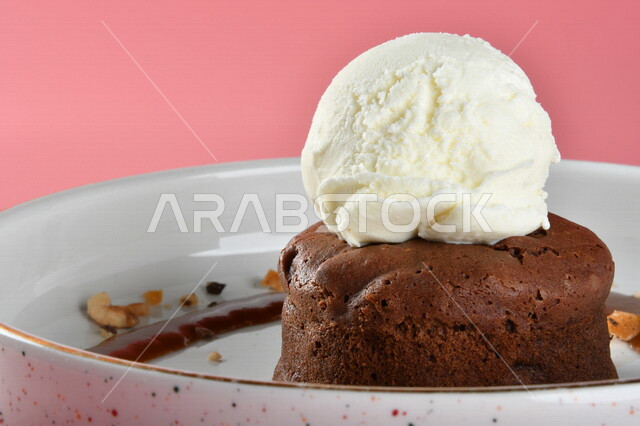 طبق من حلا كيك الشوكولاته المزينة بقطعة آيس كريم بنكهة الفانيليا ، حلا شرقي ، حلويات رمضانية ، حلويات وسكريات ، قطع الحلوى الشهية ، التحلاية ، حلويات باردة لذيذة ، خلفية ملونة