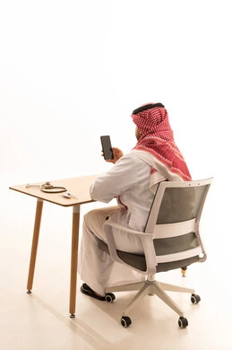 طبيب سعودي على المكتب مع هاتف ذكي وسماعة