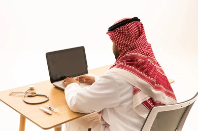 Saudi Doctor Working on Laptop with Medical Tools