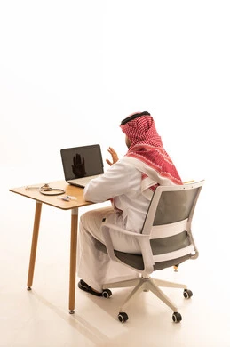 طبيب سعودي يستخدم الحاسوب المحمول في المكتب مع سماعة طبية