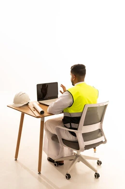 Saudi Engineer Working on Laptop with Blueprints
