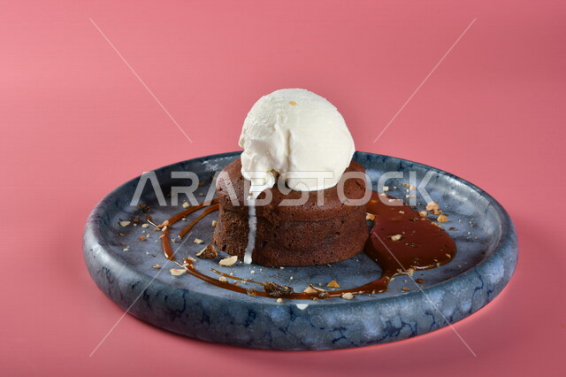 طبق من حلا كيك الشوكولاته المزينة بقطعة آيس كريم بنكهة الفانيليا ، حلا شرقي ، حلويات رمضانية ، حلويات وسكريات ، قطع الحلوى الشهية ، التحلاية ، حلويات باردة لذيذة ، خلفية ملونة