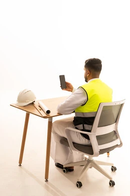 Saudi Engineer at Desk with Smartphone and Safety Gear
