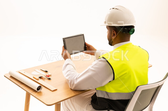 مهندس سعودي يستخدم جهاز لوحي مع معدات السلامة