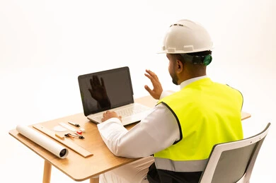 Saudi Engineer Using Laptop Wearing Safety Vest and Helmet