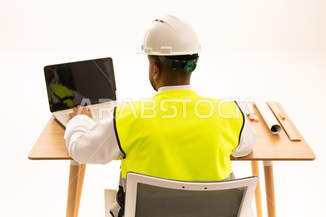 مهندس سعودي بالثوب التقليدي يستخدم الحاسوب في المكتب