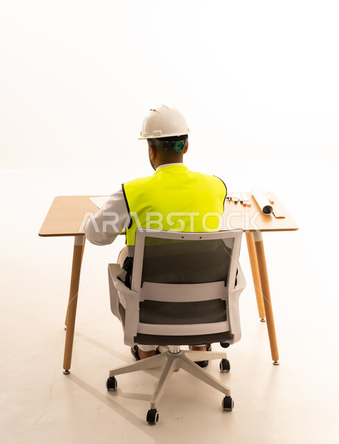 مهندس مدني سعودي بالثوب يجلس خلف مكتبه