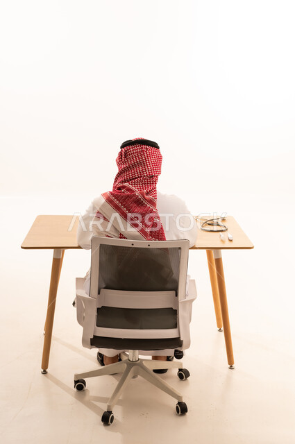 رجل سعودي بالزي التقليدي يجلس خلف مكتب طبي