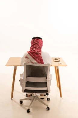 Saudi Doctor in Traditional Thobe Sitting at Desk