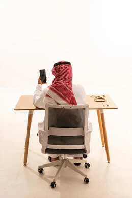 Saudi Man in Traditional Dress Using Smartphone in Office