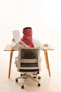 طبيب سعودي بالزي التقليدي يجلس خلف المكتب