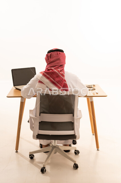 رجل سعودي يعمل على جهاز كمبيوتر في المكتب
