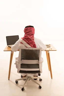 رجل سعودي يعمل على جهاز كمبيوتر في المكتب