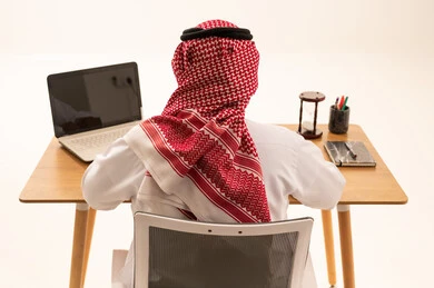 Saudi Man in Traditional Thobe Working on Laptop Back View
