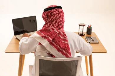 Saudi Businessman Working on Laptop at Desk Back View