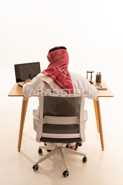 رجل سعودي يعمل على الحاسوب المحمول في المكتب