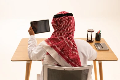 Saudi Businessman at Desk Holding Digital Tablet