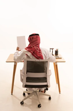 رجل سعودي بالزي التقليدي يعمل خلف مكتبه في الاستوديو