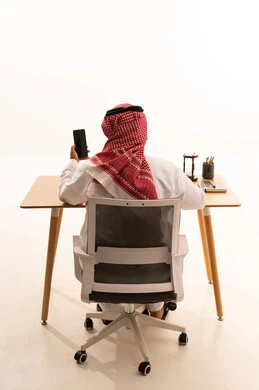 Saudi Man in Traditional Dress Working at Office Desk