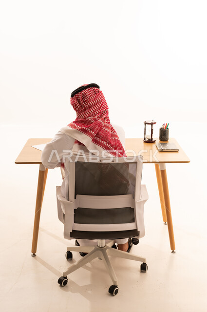 رجل سعودي بالثوب التقليدي يعمل على مكتبه