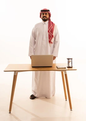 Saudi Businessman Standing at Desk with Laptop