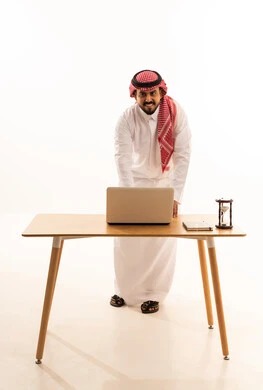 Saudi Man in Traditional Dress at Office Desk with Laptop