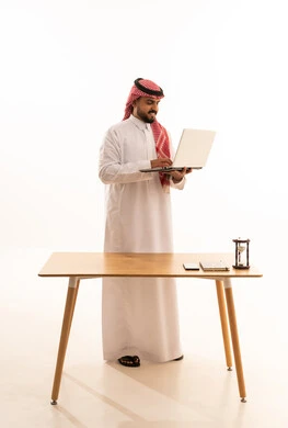 Saudi Man Using Laptop at Office Desk White Background