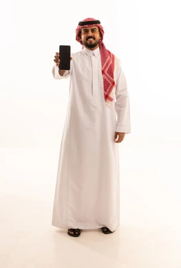 رجل سعودي بالزي التقليدي يحمل هاتف ذكي في استوديو