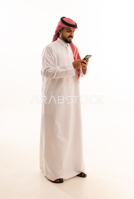 رجل سعودي بالزي التقليدي يستخدم الهاتف الذكي