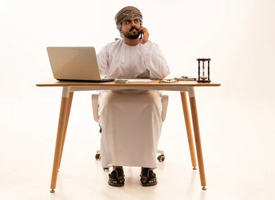 رجل عماني بالزي التقليدي يعمل على مكتبه