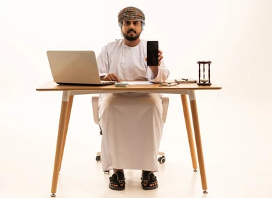 Omani Man in Traditional Dress with Smartphone and Laptop