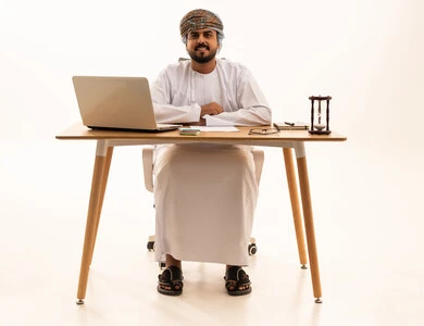 رجل أعمال عماني في المكتب مع حاسوب محمول